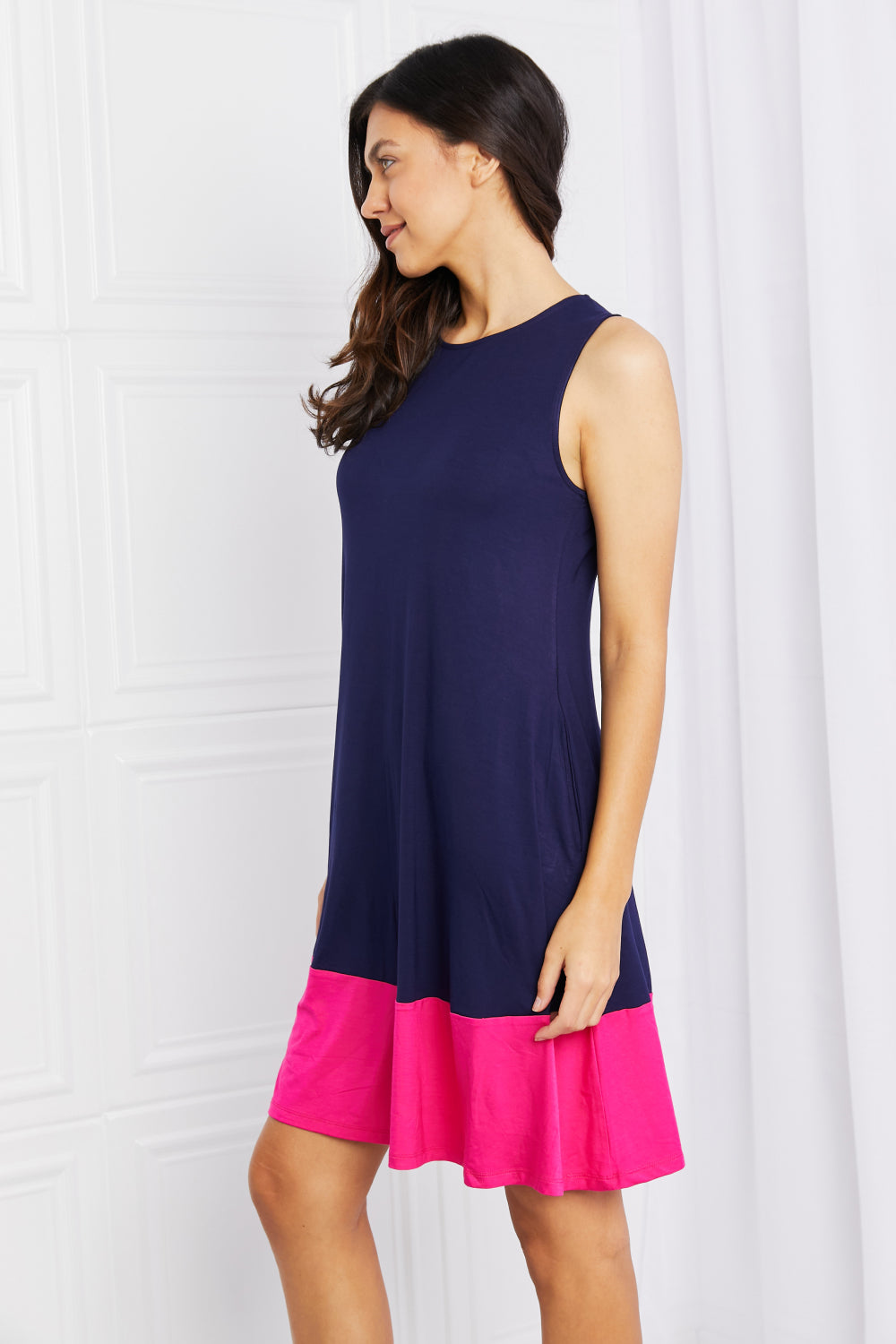 Side view of two-tone sleeveless mini dress with pockets.