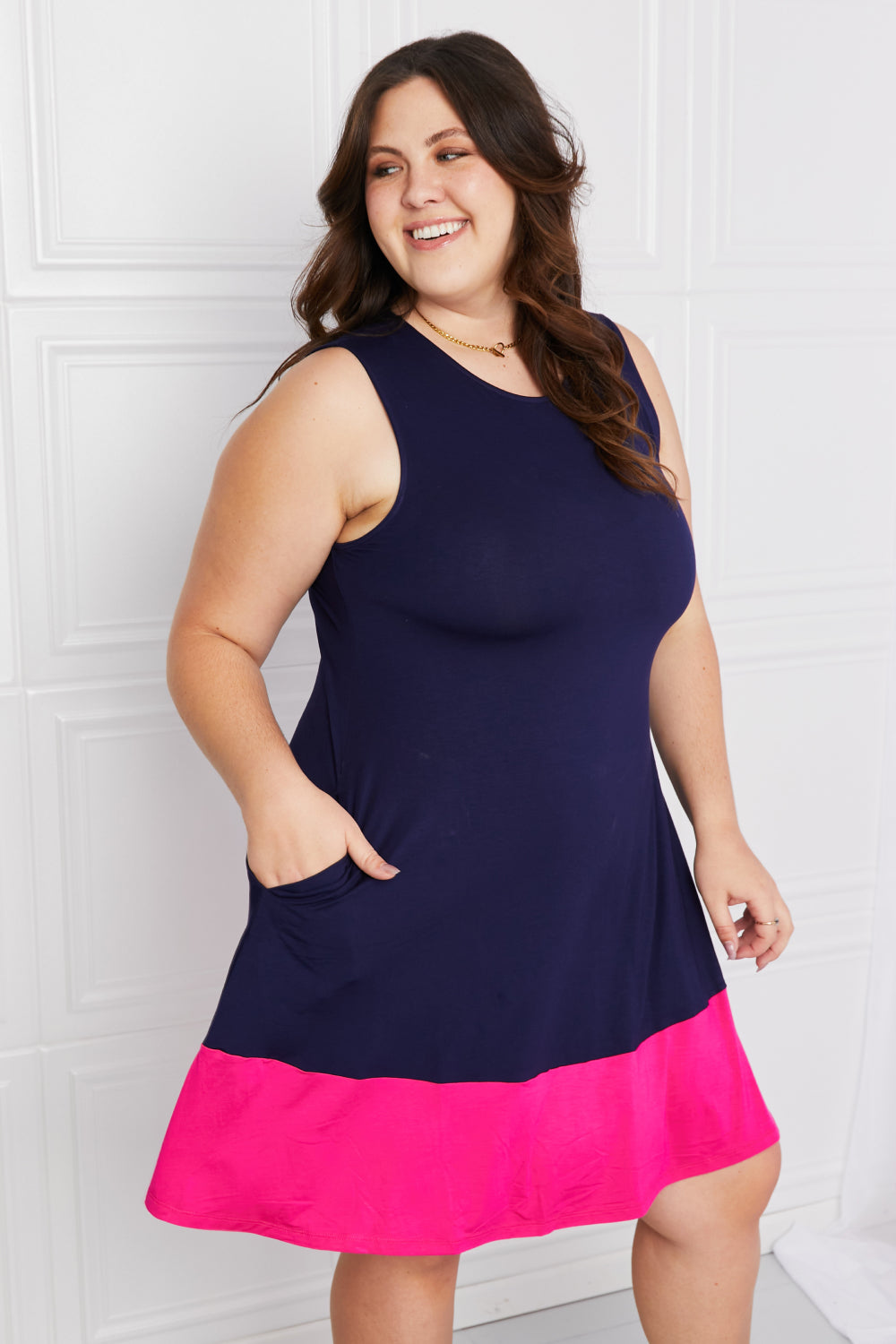 Plus-size model showing pocket detail on two-tone mini dress.