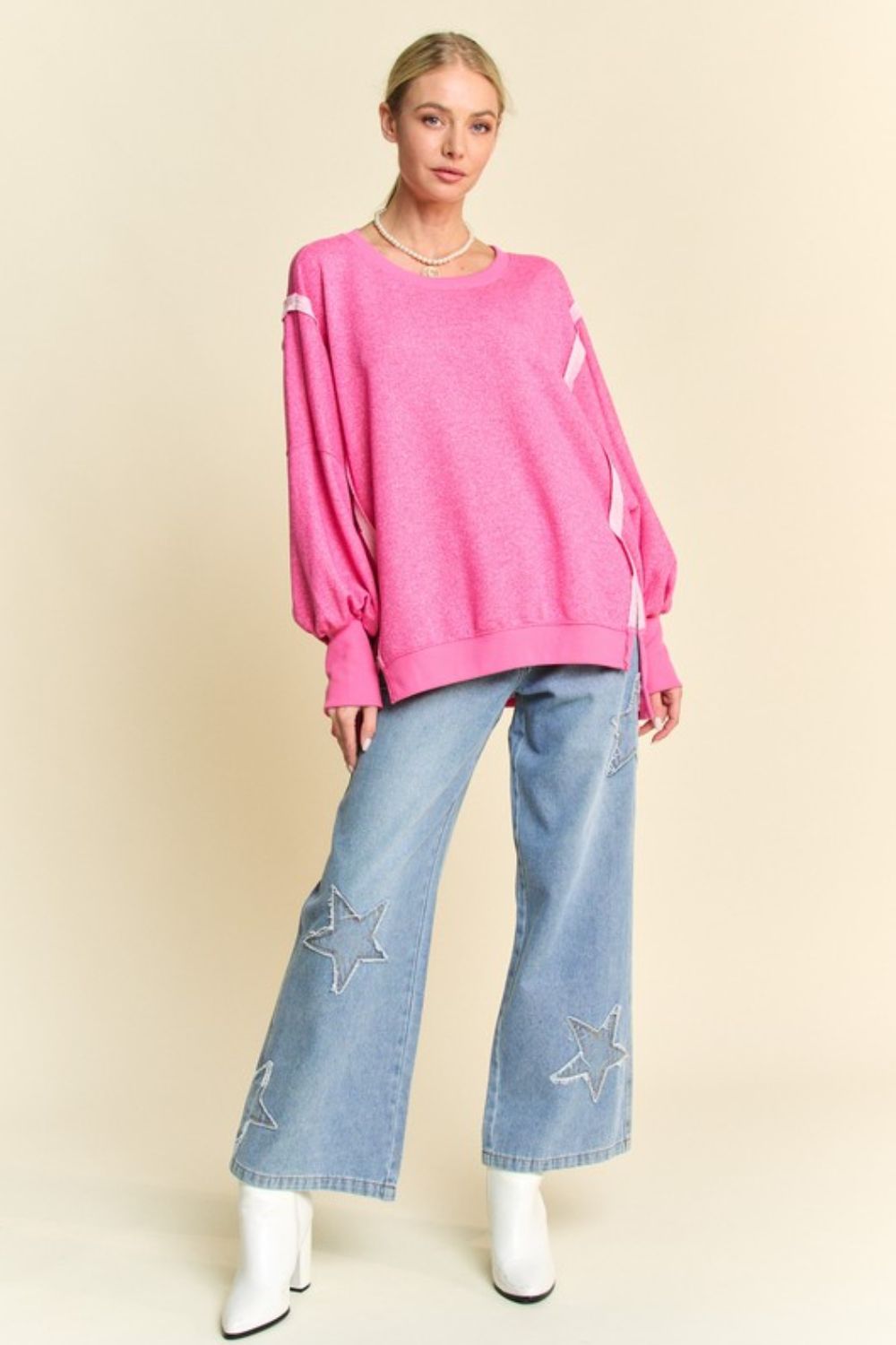 Model wearing pink knit top and star jeans, full view