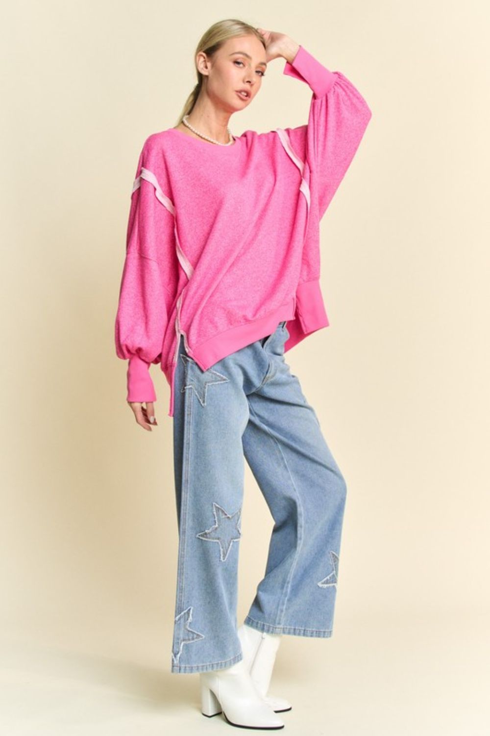 Model in pink knit top with lantern sleeves, casual pose