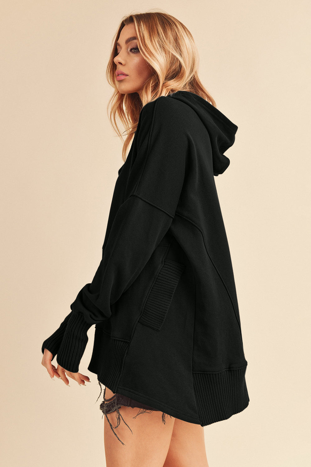 Side view of Noiré Whisper Snap Hoodie in black, showing hood and ribbed details.