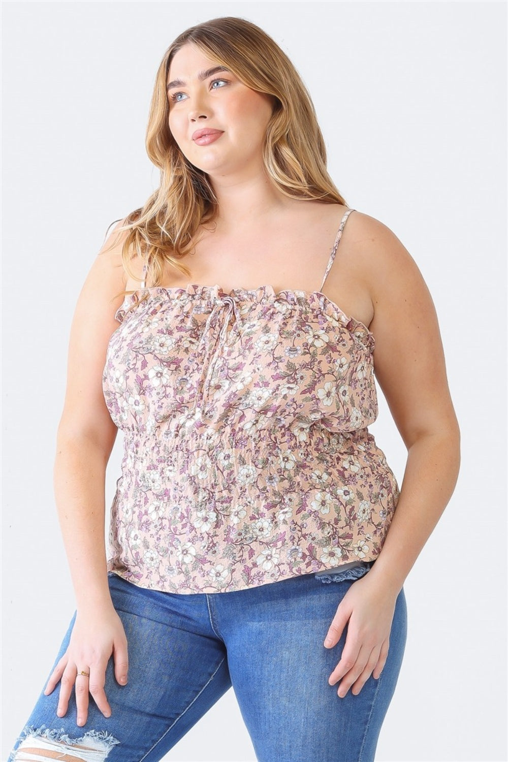 A woman in a Plus Size Cami | Zenobia Frill Floral Square Neck and ripped jeans stands against a plain background, looking to the side.