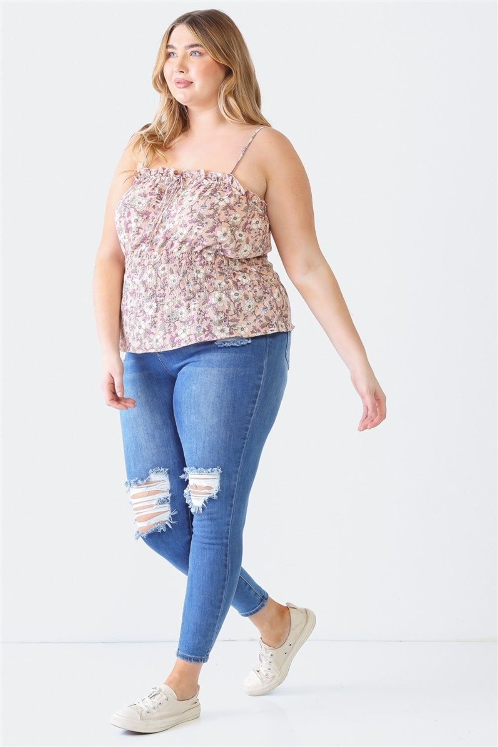 A woman wearing a Plus Size Cami | Zenobia Frill Floral Square Neck, ripped denim jeans, and white sneakers stands against a plain background.