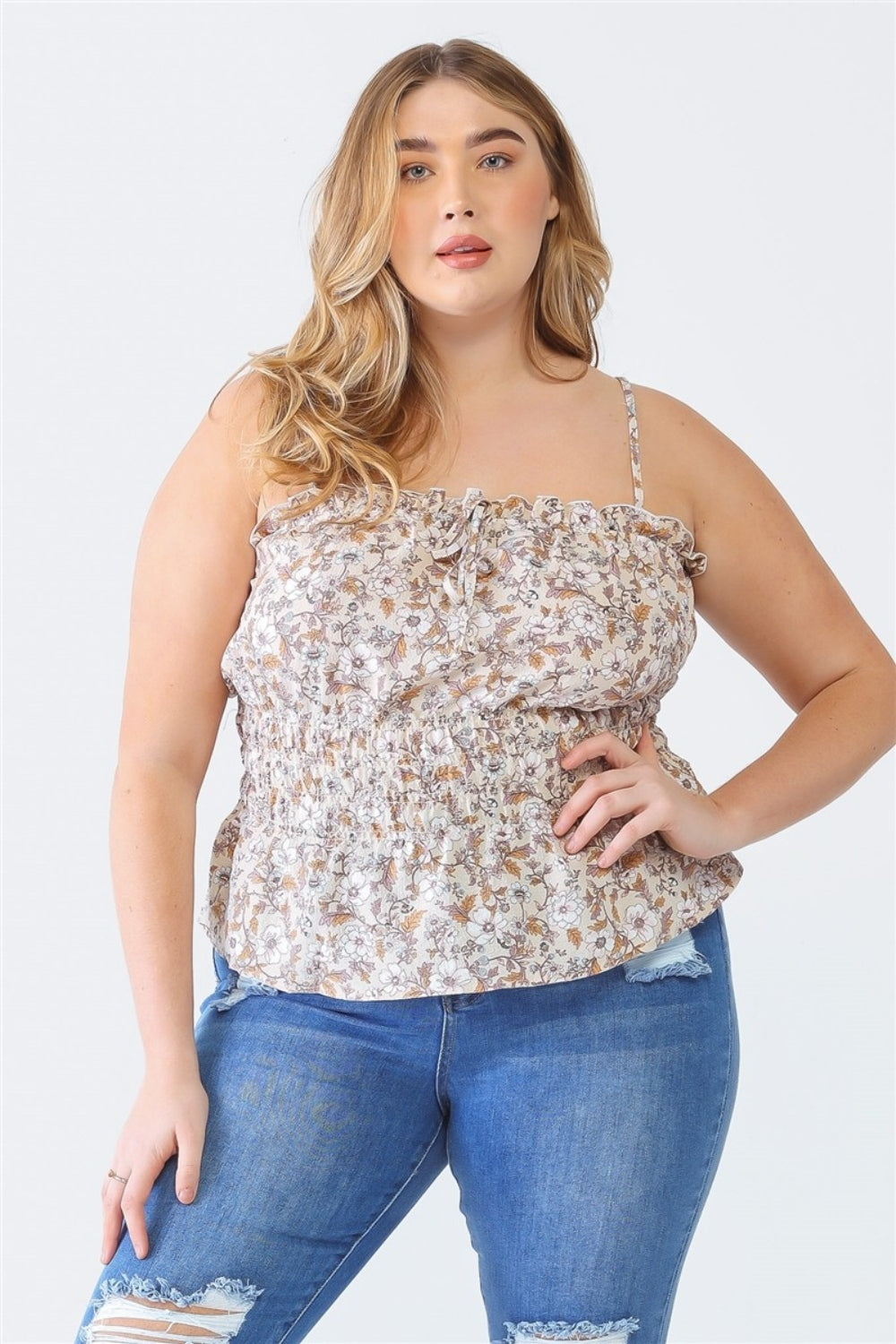 A person stands facing the camera wearing a Plus Size Cami | Zenobia Frill Floral Square Neck and ripped jeans, with one hand on their hip.